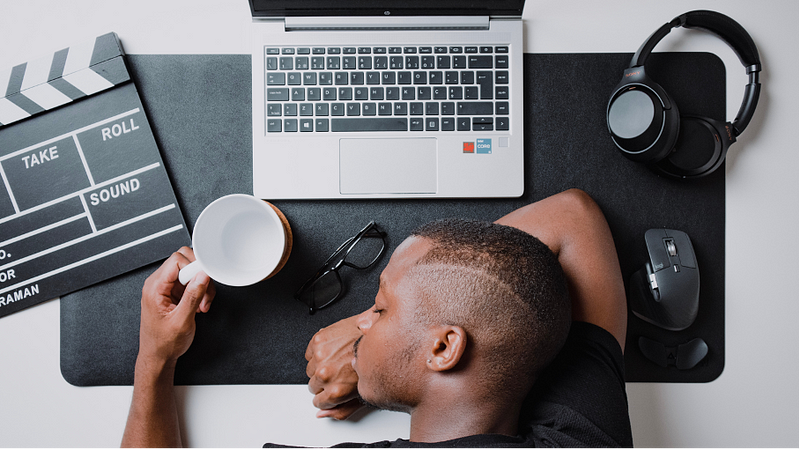 man slumped on desk procrastinating