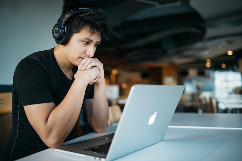 man thinking while looking at laptop