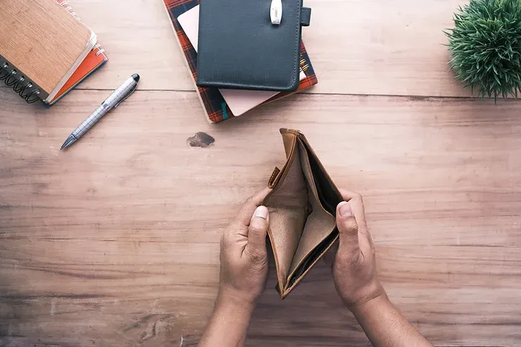 a man opening an empty wallet with a notepad on his desk